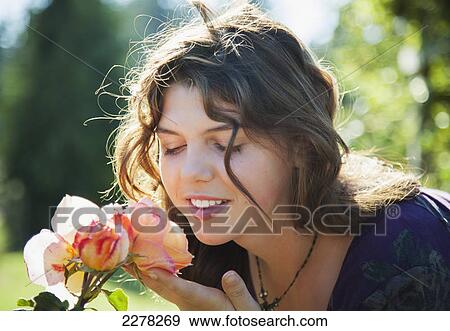 Stock Photo - A teenage girl smells a heritage rose in the late days of summer; British columbia canada. Fotosearch
