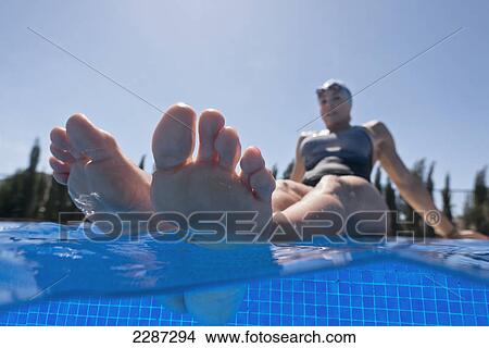 A woman soaking her feet in the swimming pool; Tarifa cadiz andalusia spain View Large Photo Image Picture - A woman soaking her feet in the swimming pool; Tarifa cadiz andalusia spain. Fotosearch