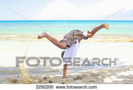 A young boy does a cartwheel in the sand at the water's edge; Hawaii united states of america View Large Photo Image Stock Image - A young boy does a cartwheel in the sand at the water's edge; Hawaii united states of america. Fotosearch