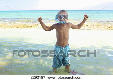 Stock Photo - A young boy in the shallow water of the ocean with snorkelling gear; Hawaii united states of america. Fotosearch
