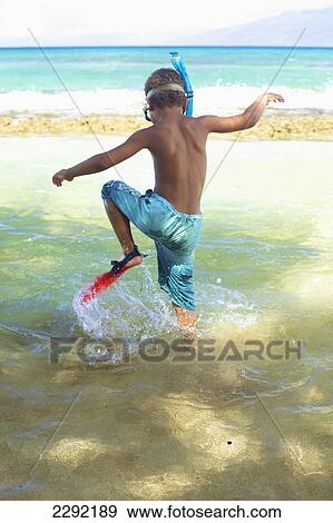 Stock Photo - A young boy in the shallow water of the ocean with snorkelling gear; Hawaii united states of america. Fotosearch