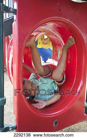 A young boy lays in a silly pose in playground equipment; Hawaii united states of america View Large Photo Image Stock Photo - A young boy lays in a silly pose in playground equipment; Hawaii united states of america. Fotosearch