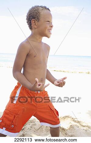 A young boy poses in a cool stance while standing in the sand by the ocean; Hawaii united states of america View Large Photo Image Stock Image - A young boy poses in a cool stance while standing in the sand by the ocean; Hawaii united states of america. Fotosearch