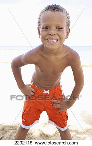A young boy poses while standing in the sand by the ocean; Hawaii united states of america View Large Photo Image Stock Photo - A young boy poses while standing in the sand by the ocean; Hawaii united states of america. Fotosearch