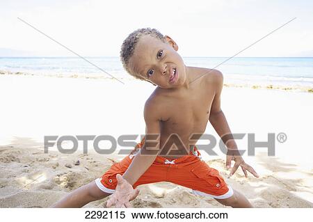 A young boy poses with a silly face while standing in the sand by the ocean; Hawaii united states of america View Large Photo Image Stock Photography - A young boy poses with a silly face while standing in the sand by the ocean; Hawaii united states of america. Fotosearch