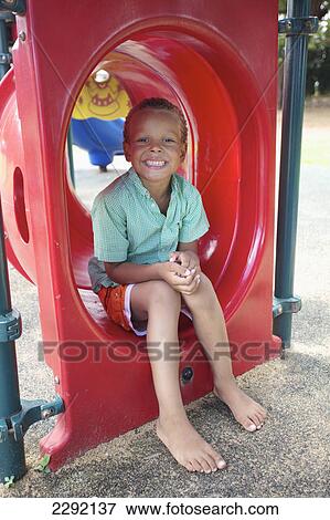A young boy sits in playground equipment; Hawaii united states of america View Large Photo Image Stock Photo - A young boy sits in playground equipment; Hawaii united states of america. Fotosearch