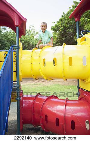 Stock Image - A young boy sits on top of playground equipment; Hawaii united states of america. Fotosearch
