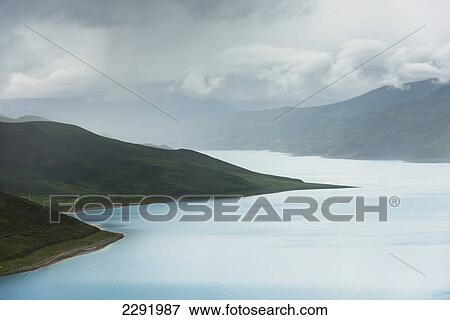 Hilly and mountainous landscape with sacred lake under a cloudy sky; Shannan xizang china View Large Photo Image Stock Photo - Hilly and mountainous landscape with sacred lake under a cloudy sky; Shannan xizang china. Fotosearch