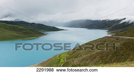 Hilly and mountainous landscape with sacred lake under a cloudy sky; Shannan xizang china View Large Photo Image Stock Photo - Hilly and mountainous landscape with sacred lake under a cloudy sky; Shannan xizang china. Fotosearch