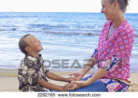 Stock Photography - Mother and son holding hands on the beach at the water's edge; Hawaii united states of america. Fotosearch