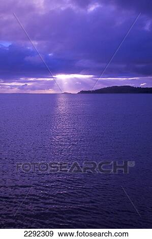 Stock Photo - Pink sunlight and sun rays reflected on the tranquil water at sunset; Hawaii united states of america. Fotosearch