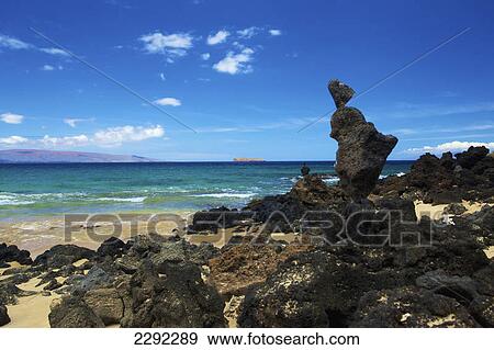 Stock Photo - Rugged black rocks sitting on the sand along the coast of an hawaiian island; Hawaii united states of america. Fotosearch