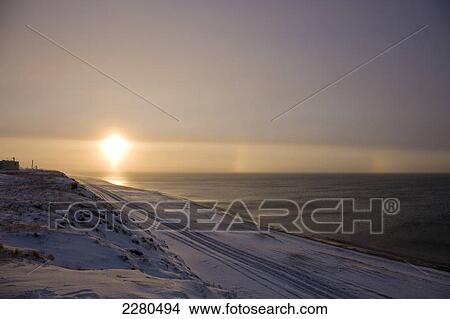 The setting sun shining through windblown snow creates two sundogs above the beaufort sea along the coast just outside of barrow in winter; Alaska united states of america View Large Photo Image Picture - The setting sun shining through windblown snow creates two sundogs above the beaufort sea along the coast just outside of barrow in winter; Alaska united states of america. Fotosearch