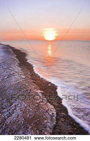 Stock Image - The setting sun shining through windblown snow creates a sundog above the beaufort sea along the coast just outside of barrow in winter; Alaska united states of america. Fotosearch