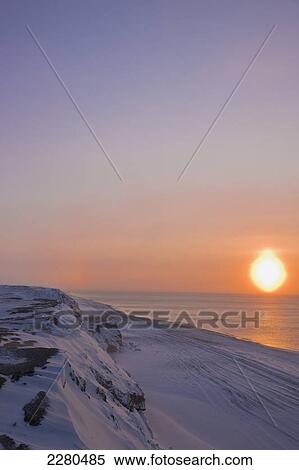 The setting sun shining through windblown snow creates a sundog above the beaufort sea along the coast just outside of barrow in winter; Alaska united states of america View Large Photo Image Stock Photography - The setting sun shining through windblown snow creates a sundog above the beaufort sea along the coast just outside of barrow in winter; Alaska united states of america. Fotosearch