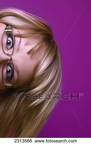 Stock Photograph - Top of a woman's head with eyeglasses peering sideways from the side of the frame with a bright pink background; Spruce grove alberta canada. Fotosearch