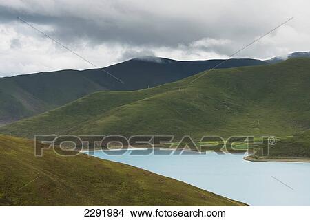 Picture - Tranquil lake in a hilly landscape under a cloudy sky; Shannan xizang china. Fotosearch