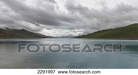 Tranquil water of sacred lake under a cloudy sky; Shannan xizang china View Large Photo Image Stock Photo - Tranquil water of sacred lake under a cloudy sky; Shannan xizang china. Fotosearch