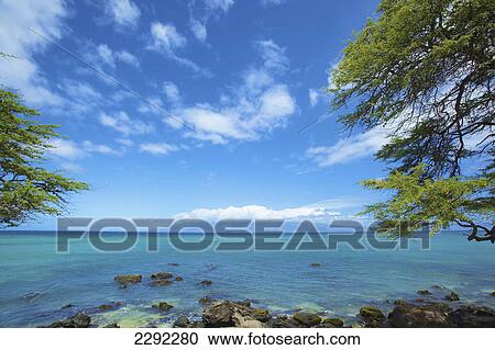 Stock Image - View of the ocean and the mountains along the coastline in the distance; Hawaii united states of america. Fotosearch