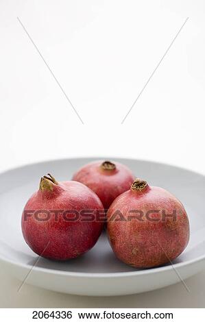 Stock Photograph - 3 Pomegranates In Low Bowl. Fotosearch