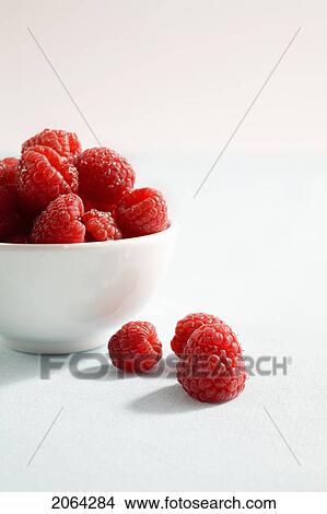 Picture - 3 Raspberries Sit Beside Bowl Of Raspberries. Fotosearch