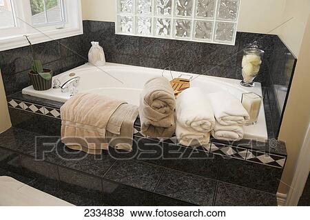 Stock Photo - A bathtub with towels folded on the edge; Oakville, Ontario, Canada. Fotosearch