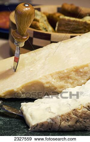 A block of parmesan and gorgonzola cheese with knives and wooden bowl of bread in the background; Calgary alberta canada View Large Photo Image Stock Photo - A block of parmesan and gorgonzola cheese with knives and wooden bowl of bread in the background; Calgary alberta canada. Fotosearch