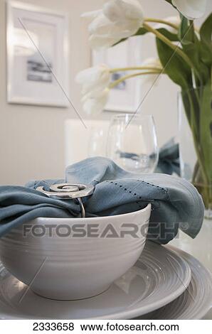 Stock Photo - A bowl and plate set with a blue fabric napkin in a napkin holder; Surrey, British Columbia, Canada. Fotosearch