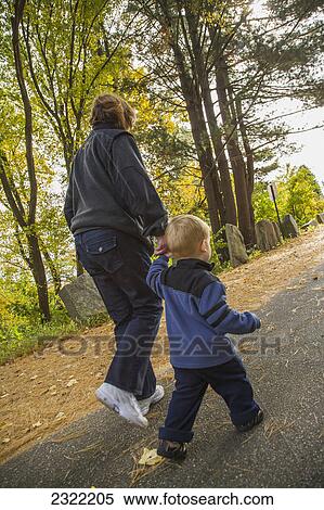 A child walks on a paved road in a park holding his grandmother's hand; Willimantic connecticut united states of america View Large Photo Image Stock Photography - A child walks on a paved road in a park holding his grandmother's hand; Willimantic connecticut united states of america. Fotosearch