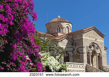 Stock Image - A church building with bright pink flowers in the foreground; Paphos cyprus. Fotosearch
