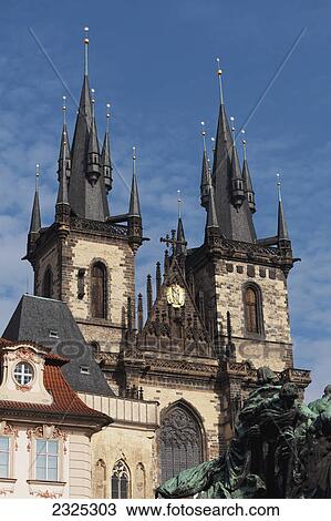 Stock Image - A church building with two towers and multiple spires and a statue in the foreground; Prague czech republic. Fotosearch