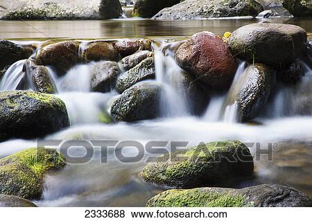 Stock Photo - A close up of water in a river spilling over rocks; Maui, Hawaii, United States of America. Fotosearch