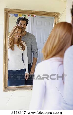 Stock Photo - A Couple Looking At A Reflection Of Themselves In A Mirror; Wailua Kauai Hawaii United States Of America. Fotosearch