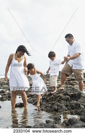 A family all wearing white walks over the rocks at the water's edge; Honolulu oahu hawaii united states of america View Large Photo Image Picture - A family all wearing white walks over the rocks at the water's edge; Honolulu oahu hawaii united states of america. Fotosearch