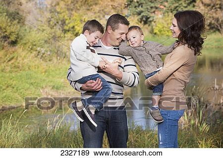 Stock Photo - A family spending time together in a park in autumn; St. albert alberta canada. Fotosearch