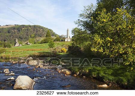 A flowing creek with a round tower in the distance; Glendalough county wicklow ireland View Large Photo Image Stock Photo - A flowing creek with a round tower in the distance; Glendalough county wicklow ireland. Fotosearch