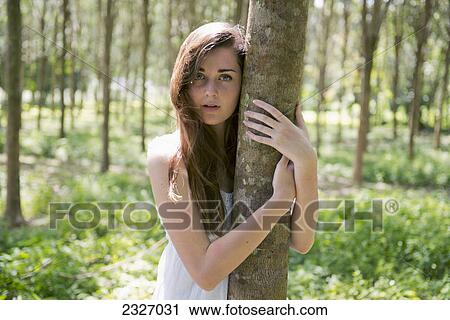 A girl in the woods hugging a tree trunk; Phuket thailand View Large Photo Image Stock Image - A girl in the woods hugging a tree trunk; Phuket thailand. Fotosearch