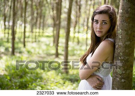Stock Image - A girl in the woods leaning on a tree trunk; Phuket thailand. Fotosearch