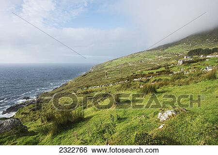 Stock Photograph - A grassy slope along the coast and the farms of bolus head; Ballinskelligs county kerry ireland. Fotosearch