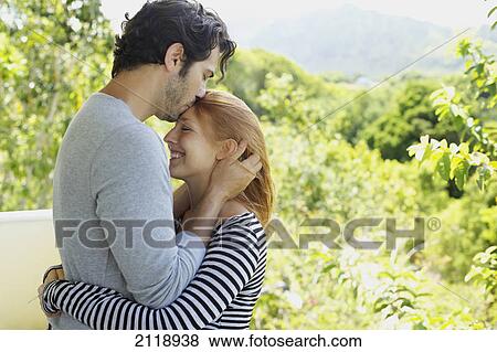 Stock Photo - A Man And Woman In An Embrace As He Kisses Her Forehead; Wailua Kauai Hawaii United States Of America. Fotosearch
