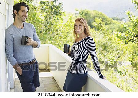 A Man And Woman Standing On A Balcony With Their Coffee Mugs; Wailua Kauai Hawaii United States Of America View Large Photo Image Picture - A Man And Woman Standing On A Balcony With Their Coffee Mugs; Wailua Kauai Hawaii United States Of America. Fotosearch
