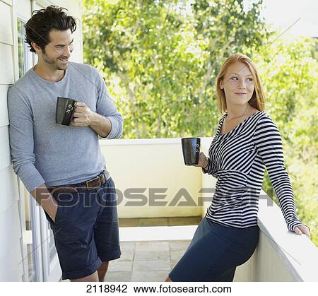 Stock Image - A Man And Woman Standing On A Balcony With Their Coffee Mugs; Wailua Kauai Hawaii United States Of America. Fotosearch