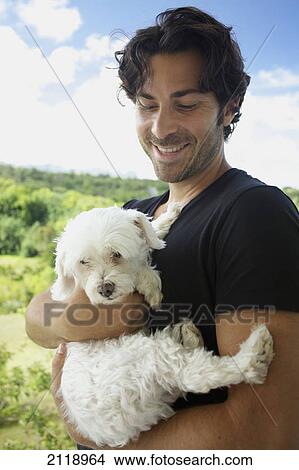 Picture - A Man Holding A Dog; Wailua Kauai Hawaii United States Of America. Fotosearch