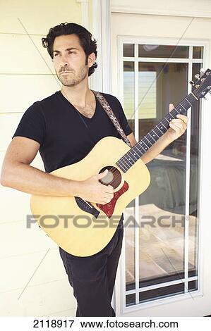 A Man Playing His Guitar Outside His House; Wailua Kauai Hawaii United States Of America View Large Photo Image Stock Photo - A Man Playing His Guitar Outside His House; Wailua Kauai Hawaii United States Of America. Fotosearch