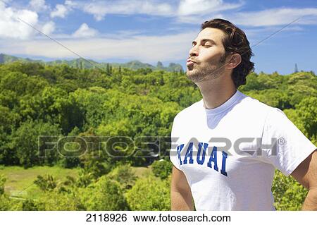 Stock Photograph - A Man Puckering His Lips As He Looks Up With The Sun Shining On His Face; Wailua Kauai Hawaii United States Of America. Fotosearch