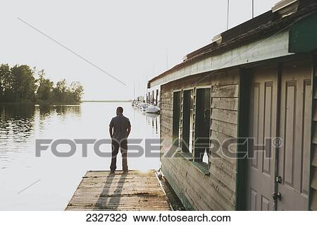 A man standing on the edge of a dock looking out over the ocean; White rock british columbia canada View Large Photo Image Stock Photo - A man standing on the edge of a dock looking out over the ocean; White rock british columbia canada. Fotosearch