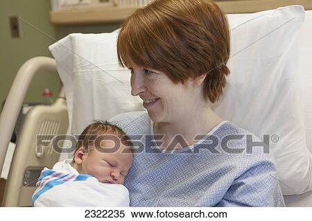 Stock Photography - A mother holds her newborn baby in a hospital bed; Willimantic connecticut united states of america. Fotosearch