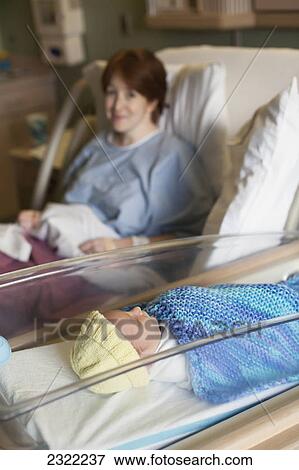 A newborn baby boy rests in a hospital bassinet next to the baby's mother who is looking on from her hospital bed following the delivery; Willimantic connecticut united states of america View Large Photo Image Stock Photo - A newborn baby boy rests in a hospital bassinet next to the baby's mother who is looking on from her hospital bed following the delivery; Willimantic connecticut united states of america. Fotosearch