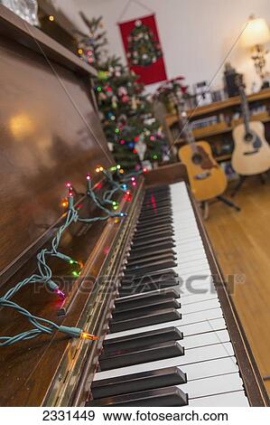 A piano decorated with christmas lights with guitars on stands in the background; Anchorage alaska united states of america View Large Photo Image Stock Photo - A piano decorated with christmas lights with guitars on stands in the background; Anchorage alaska united states of america. Fotosearch