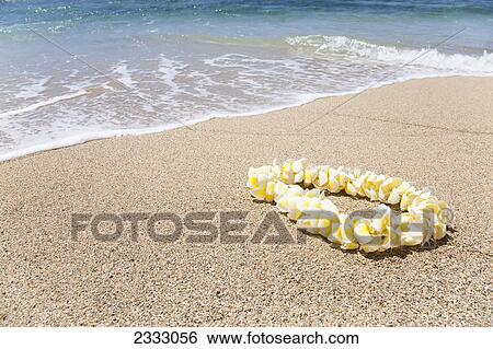 Stock Photograph - A plumeria flower lei on the beach; Honolulu oahu hawaii united states of america. Fotosearch